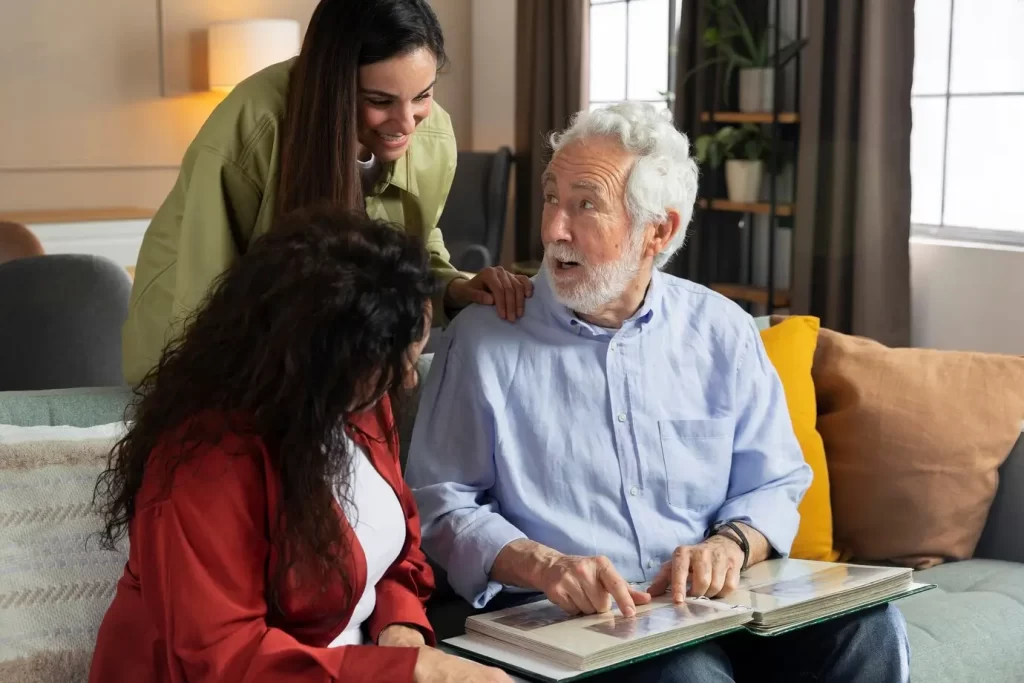 senior man with younger aged care professional women on couch